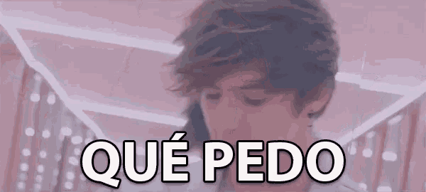 a man is standing in front of a sign that says qué pedo