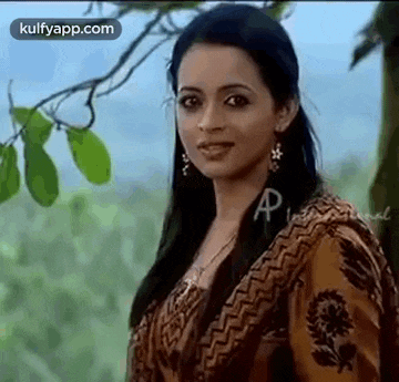 a woman is standing in front of a tree and smiling .