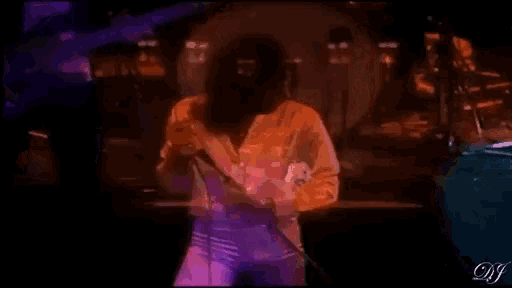 a man is singing into a microphone on a stage with a drum in the background .