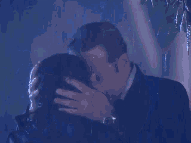 a man and a woman are kissing in the rain at night .