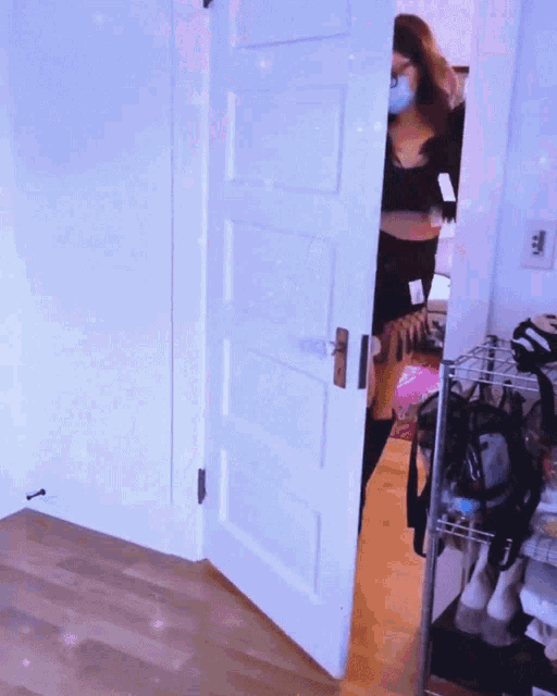 a woman wearing a mask stands in a doorway