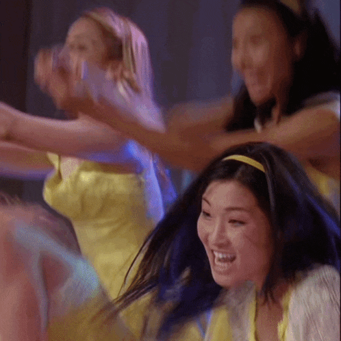 a woman with blue hair is smiling while dancing with other women