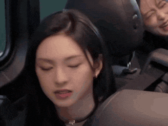 a woman is sitting in the back seat of a car with her eyes closed and her tongue sticking out .