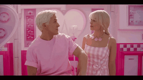 a man in a pink shirt and a woman in a pink dress are standing next to each other