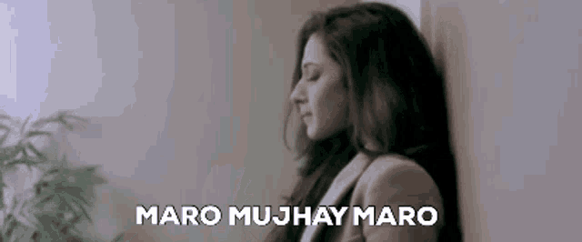 a woman is leaning against a wall with her eyes closed and the words maro mujhay maro on the bottom .