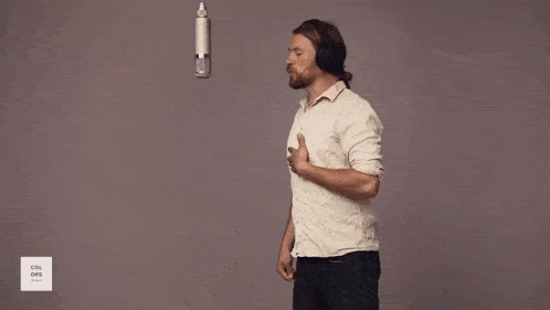 a man in a white shirt is standing on a black mat in front of a microphone that says cool chris