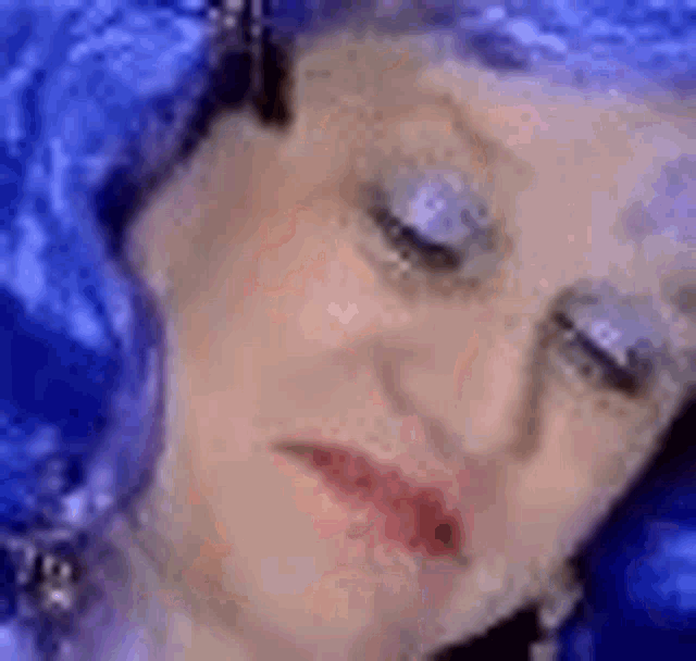 a close up of a woman 's face with a blue wig and earrings .