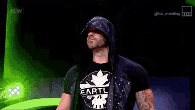a wrestler is covering his face with his hand while wearing a black mask .