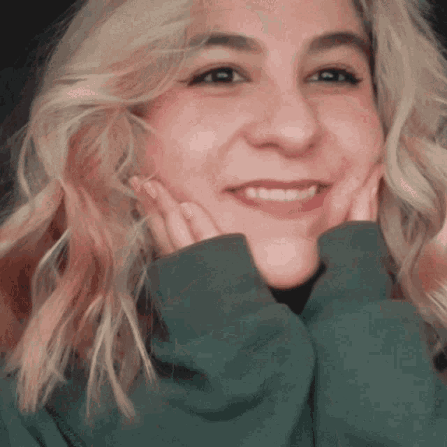 a close up of a woman 's face with her hands on her cheeks
