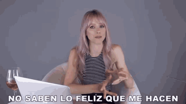 a woman with pink hair is sitting in front of a laptop with the words no saben lo feliz que me hacen on the bottom