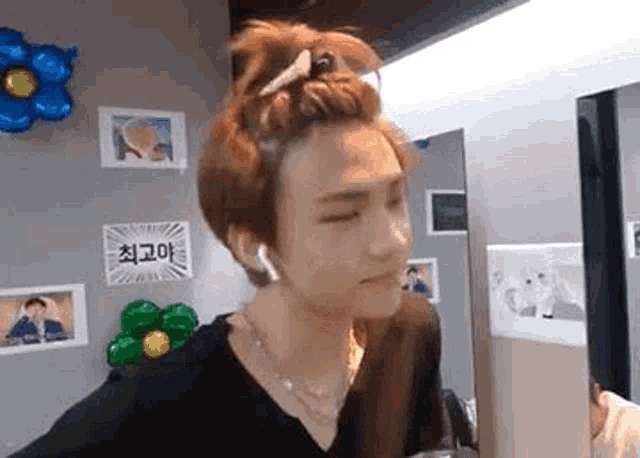a young man with a bun on his head is wearing headphones and a necklace .