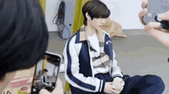 a person is taking a picture of a young man sitting on the floor .