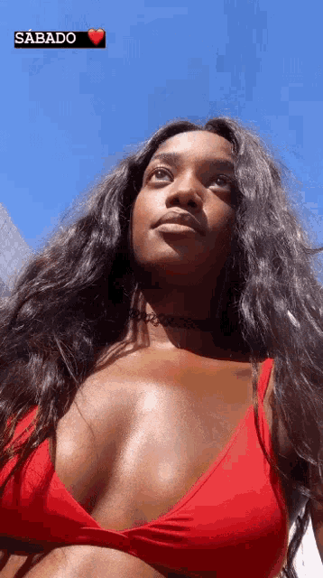 a woman in a red bikini top is looking up at the sky