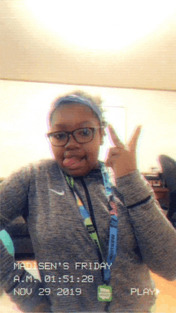 a girl wearing glasses and a nike lanyard is giving the peace sign