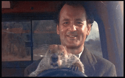 a man in a suit is holding a squirrel in his lap