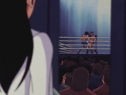 two men are boxing in a ring and a woman is watching