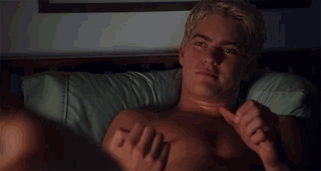 a shirtless blonde man is laying in bed with his eyes closed