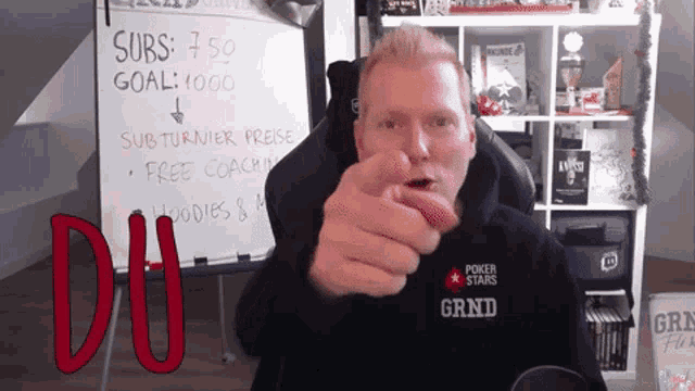 a man wearing a shirt that says grind points at the camera