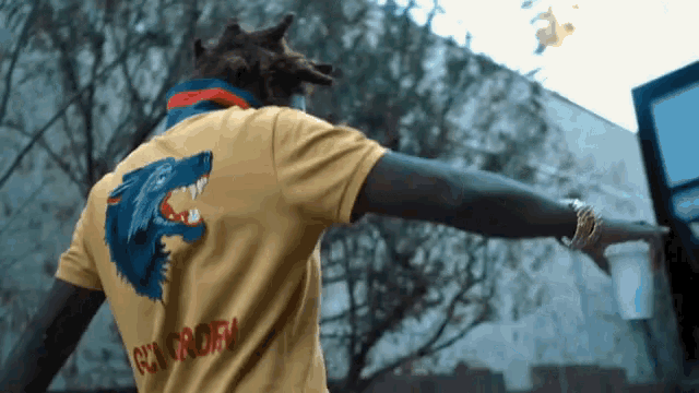 a man wearing a yellow shirt with a wolf on the back and the word gucci on it