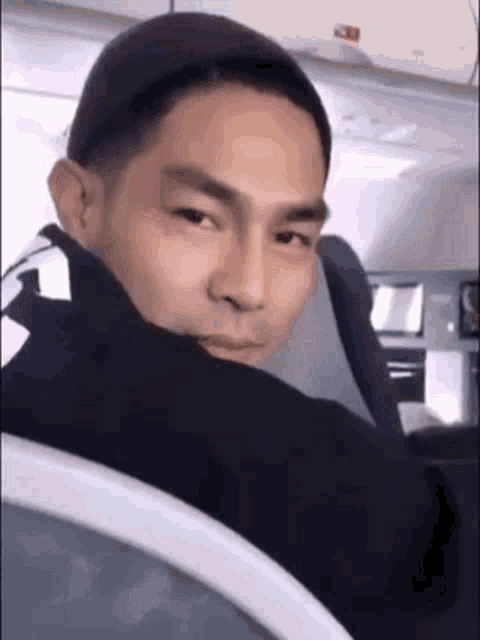 a man is sitting on an airplane and looking over his shoulder at the camera