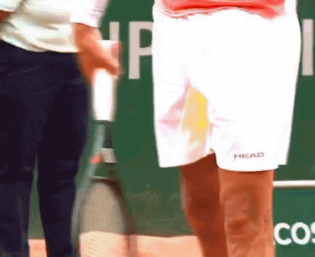 a person wearing a pair of head shorts is holding a tennis racquet