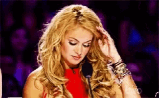 a woman with blonde hair is holding her hand to her head