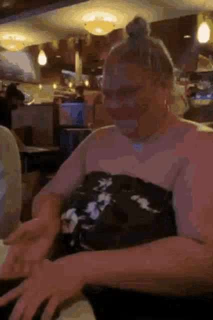 a woman in a strapless dress is sitting at a table in a restaurant with her hands outstretched .