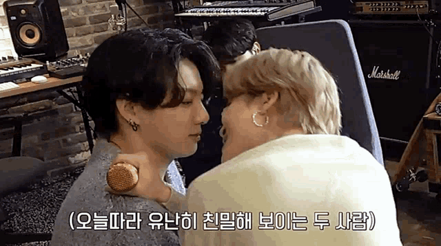 two men are kissing in front of a marshall amplifier