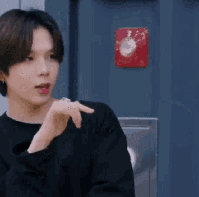 a man in a black sweater is pointing at something in front of a blue door .
