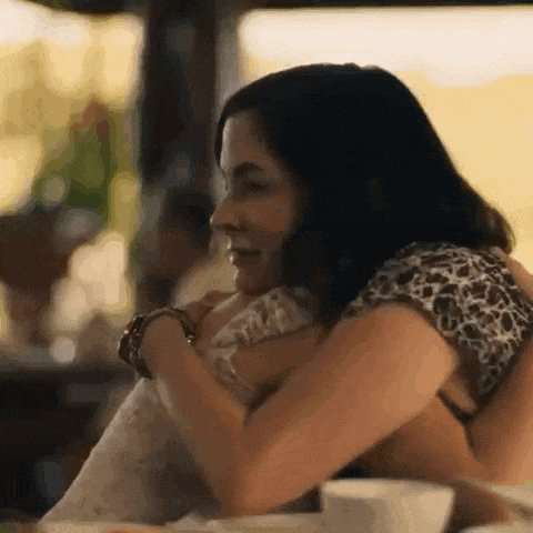 two women are hugging each other in a restaurant .