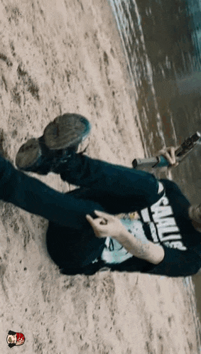 a man is laying on the beach wearing a shirt that says ' sanity ' on it