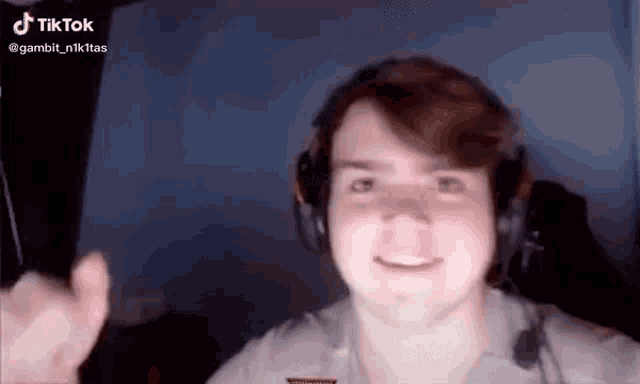 a man wearing headphones is giving a thumbs up while looking at the camera .