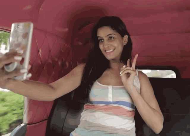 a woman taking a picture of herself with a cell phone