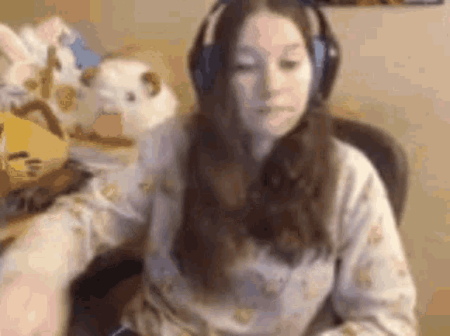 a woman wearing headphones is sitting at a desk with a stuffed animal .