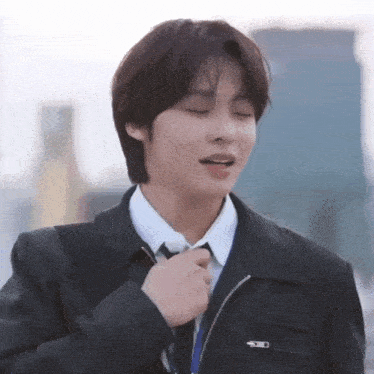 a young man in a suit and tie is adjusting his jacket .
