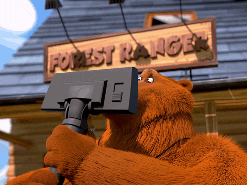 a brown bear is standing in front of a wooden sign that says forest ranger