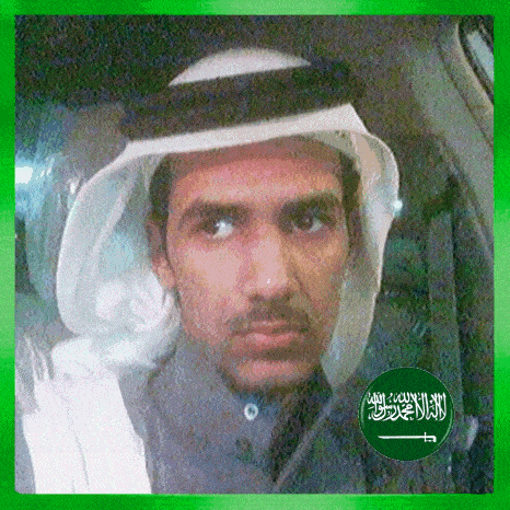 a man wearing a white head scarf and a green circle with the arabic flag on it