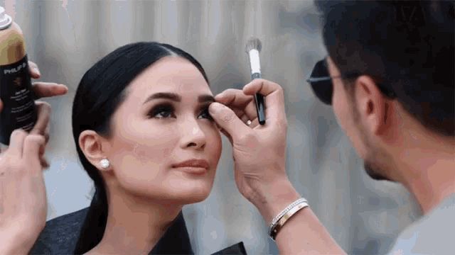 a man is applying makeup to a woman 's face with a brush