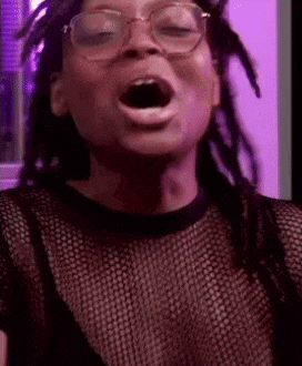 a woman wearing glasses and a black shirt is making a funny face .