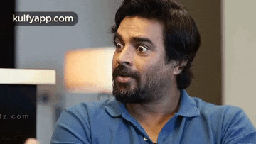 a man with a beard wearing a blue shirt is making a funny face .