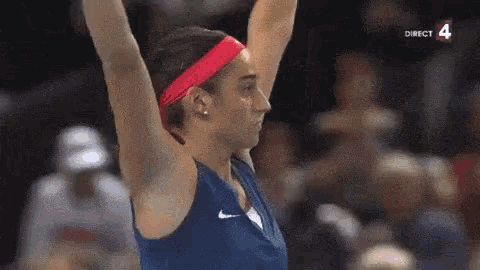 a woman with her arms in the air wearing a red headband .