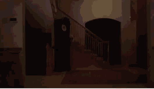 a woman is walking down a set of stairs in a dark room .
