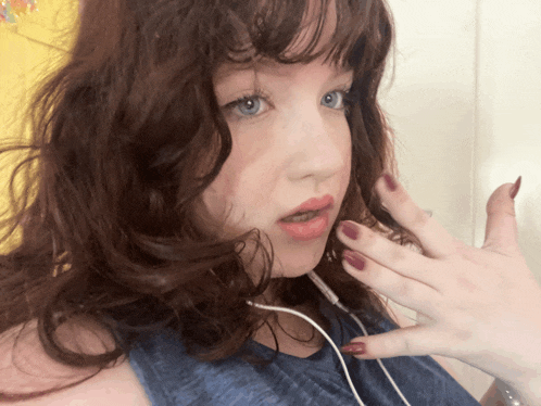 a woman with red nails is wearing headphones and a blue shirt