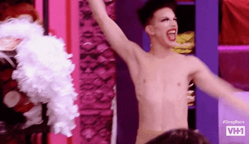 a shirtless drag queen is dancing on a stage with his arms outstretched .