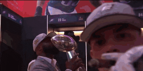 a man wearing a hat with the number 23 on it is holding a trophy