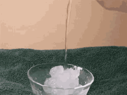 a bowl of ice is being poured into a glass bowl .