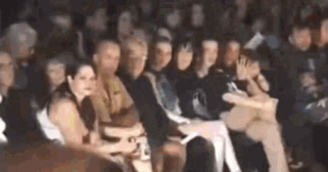 a crowd of people sitting in a row at a fashion show .