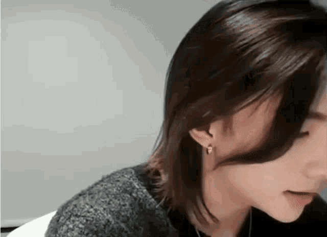 a close up of a person with long hair wearing earrings and a sweater .