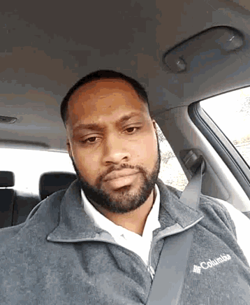 a man wearing a columbia vest is sitting in the back seat of a car