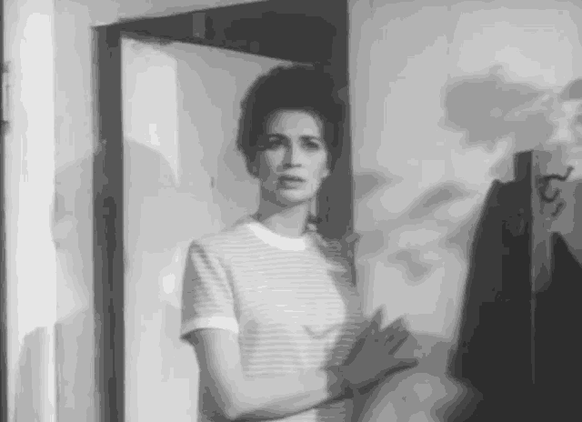 a black and white photo of a woman standing in front of a door